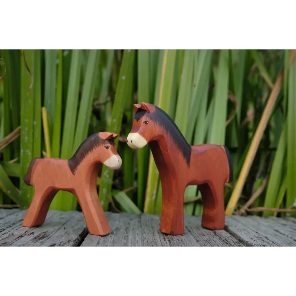 Zwei Holzpferde-Figuren, erwachsenes und Fohlen, braune Körper, schwarze Mähnen und Schwänze