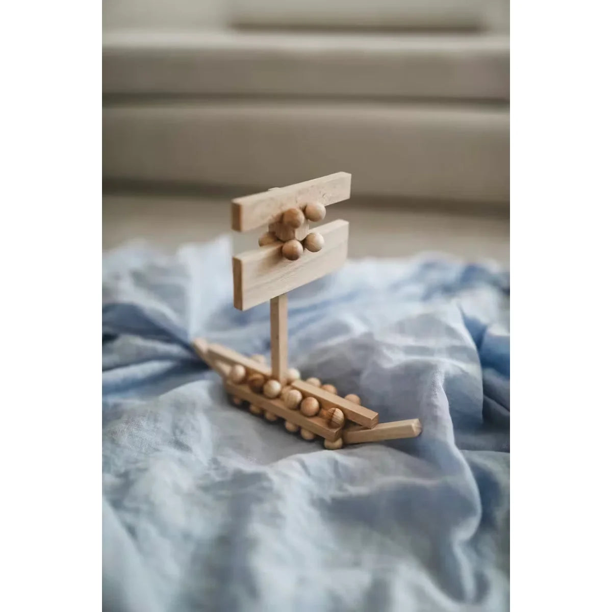 Minimalistisches Holzspielzeugboot Plus 50 mit Brixis und Twister auf blauem Stoff