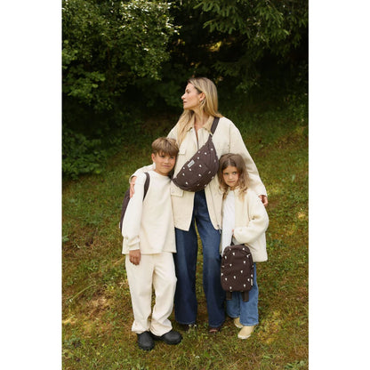 Mutter und zwei Kinder in stilvollen, abgestimmten Outfits mit braunen Herztaschen