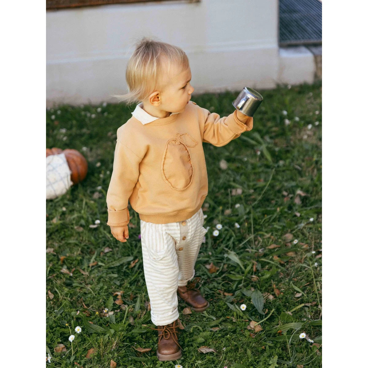 Kind in beigener Strickpullover mit Kürbis, snug pull-on Hose gestreift