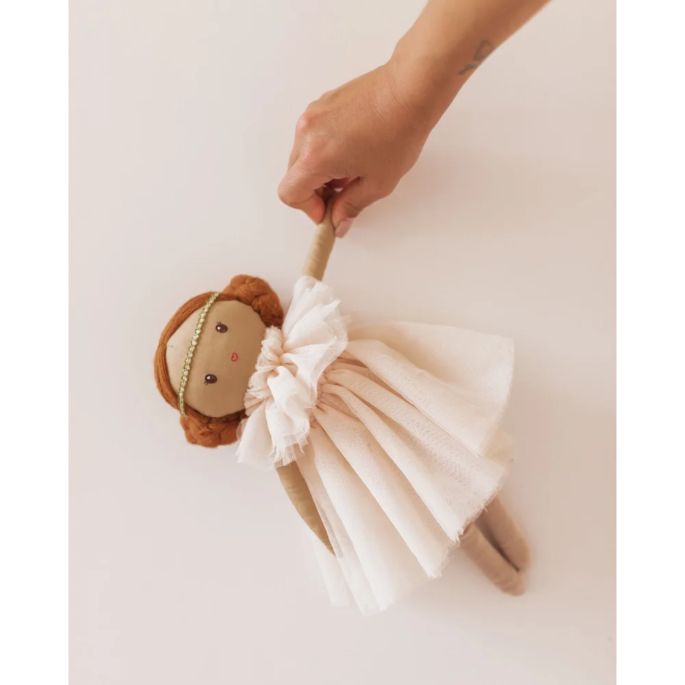 Weiche Plüschpuppe mit braunen Haaren im weißen Kleid, von einer Hand gehalten