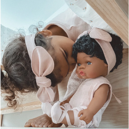 Baby und Puppe Loreta im weißen Outfit mit rosa Haarschleifen