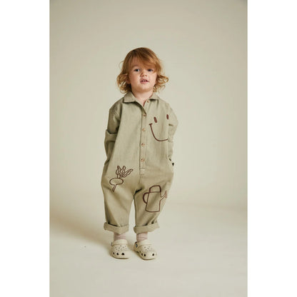 Ein beige overall quinn olive allotment mit langen ärmeln und stickereien von lachgesichtern und gartengeräten