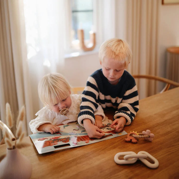 Zwei junge Kinder spielen mit einem Buch und Spielzeug aus dem Reusable Sticker Set Dino