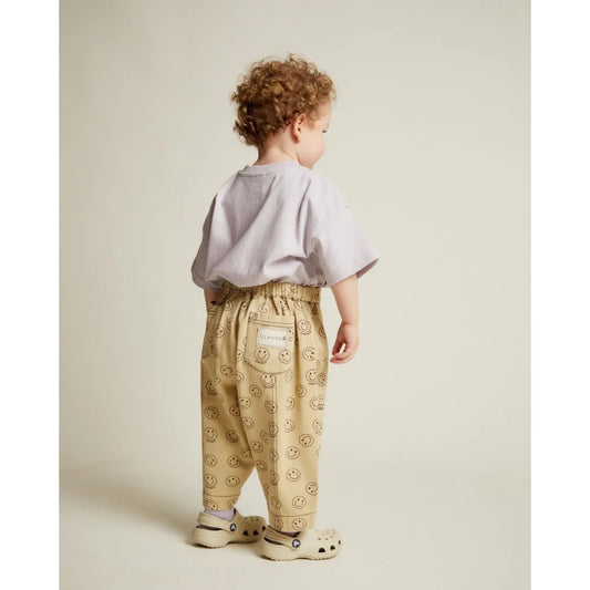Beige rex joy butter trousers mit elastischem bund und schwarzem smiley muster auf der rückseite mit markenpatch