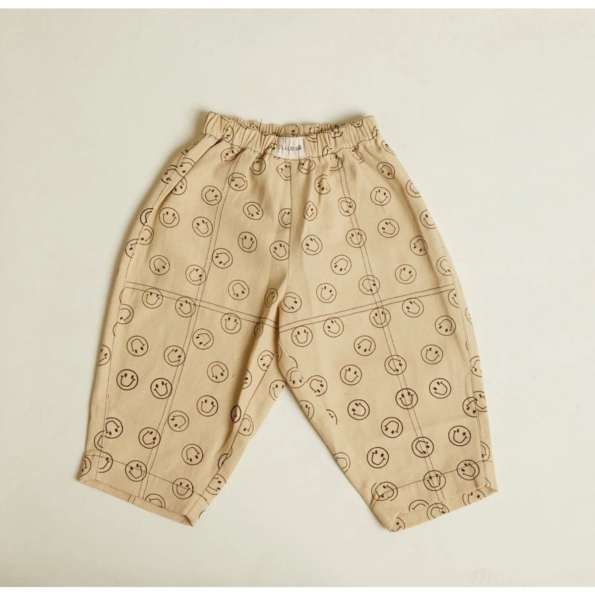 Beige rex joy butter kinderhose mit spielerischem muster aus schwarzen smileys und überkreuzten linien
