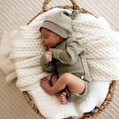 Schlafendes Baby in grünem Outfit und Mütze in einem Korb mit Ribbed Beanie von Dewkist