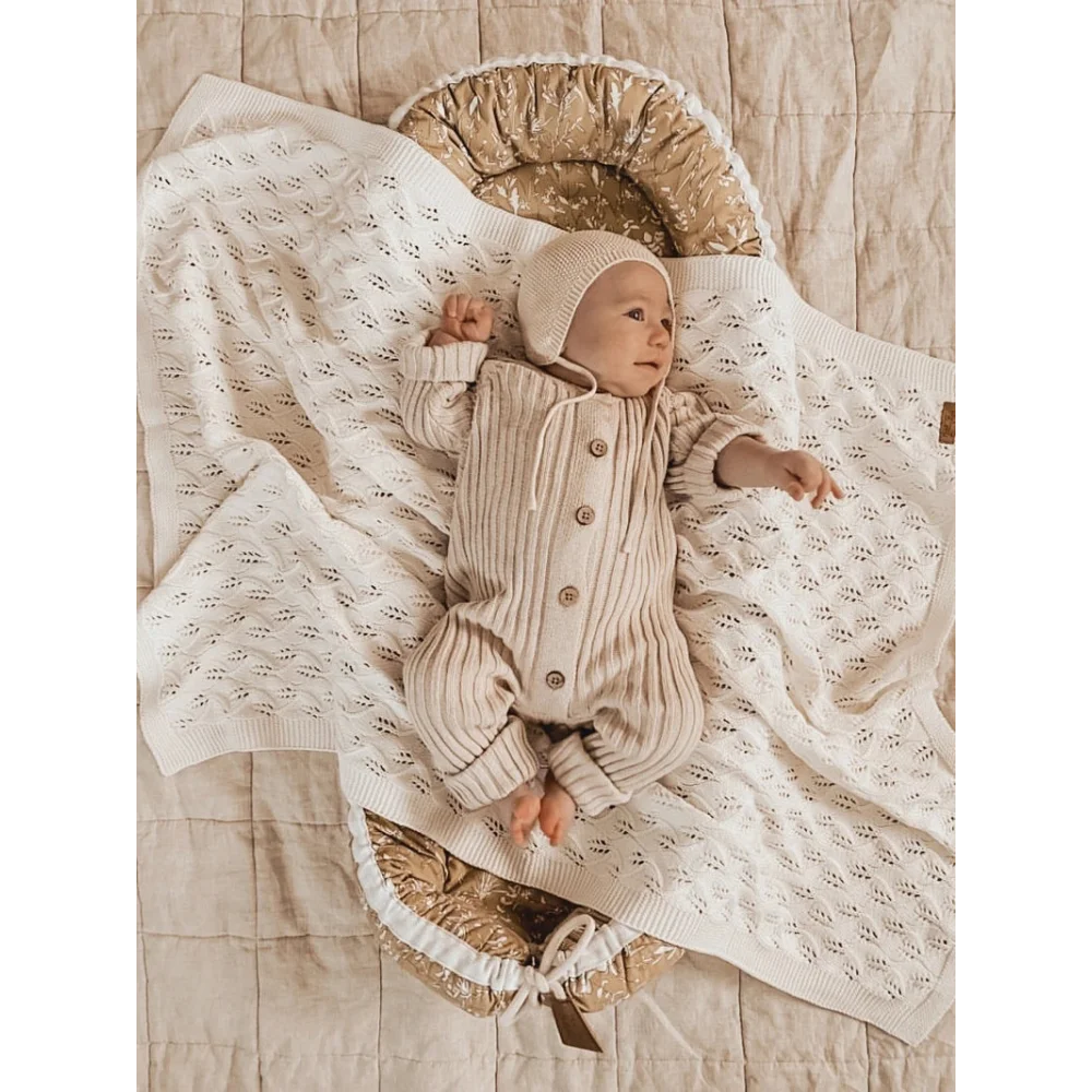 Baby in ribbed Honey Milk romper lying on a soft white blanket