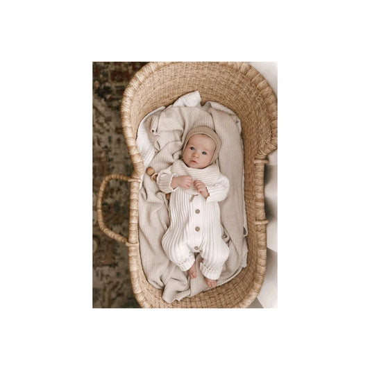 Baby in a woven basket cradle wearing a white knitted Ribbed Romper Milk