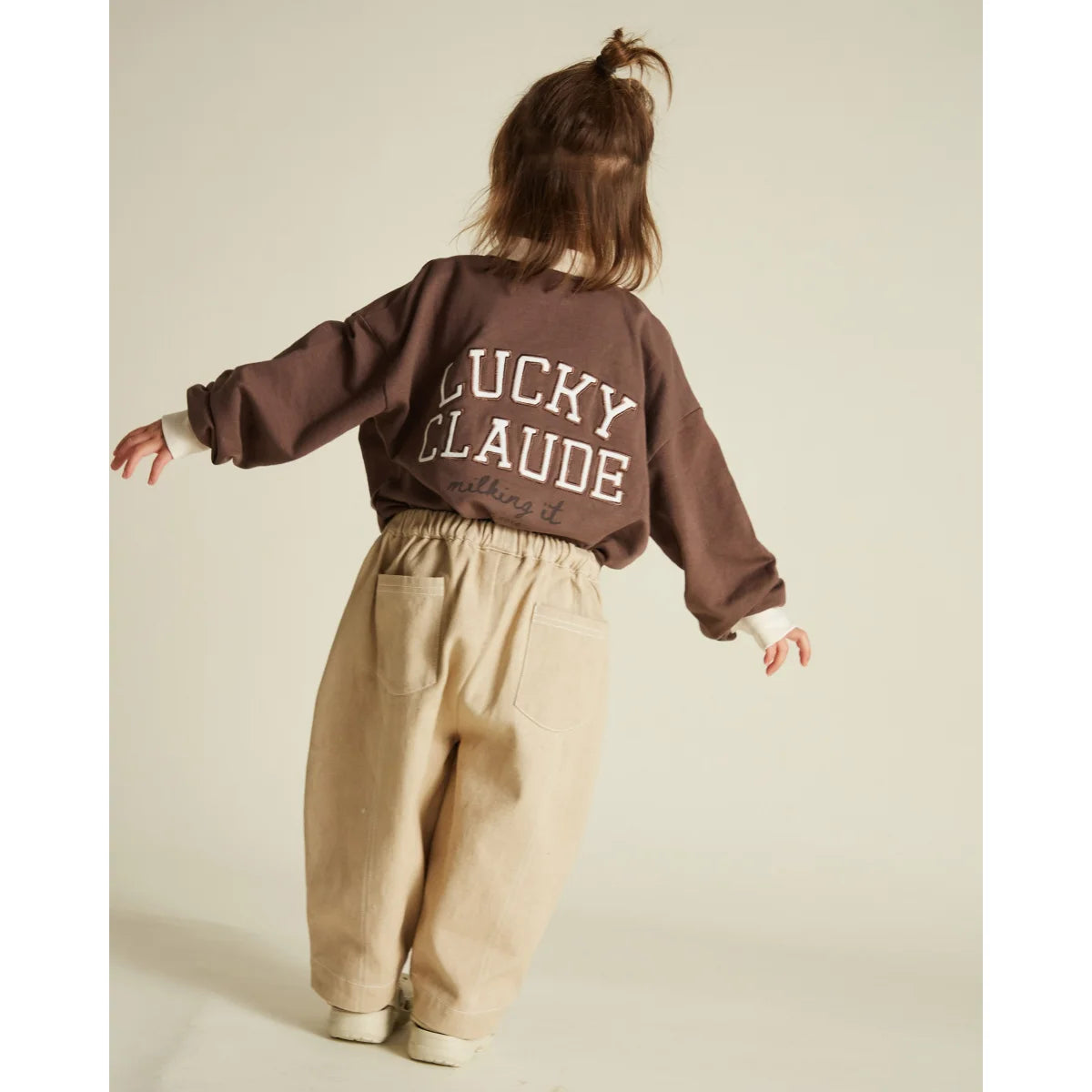 Braunes Langarm-Sweatshirt mit ’lucky claude’ in weißer Schrift über den Rücken.