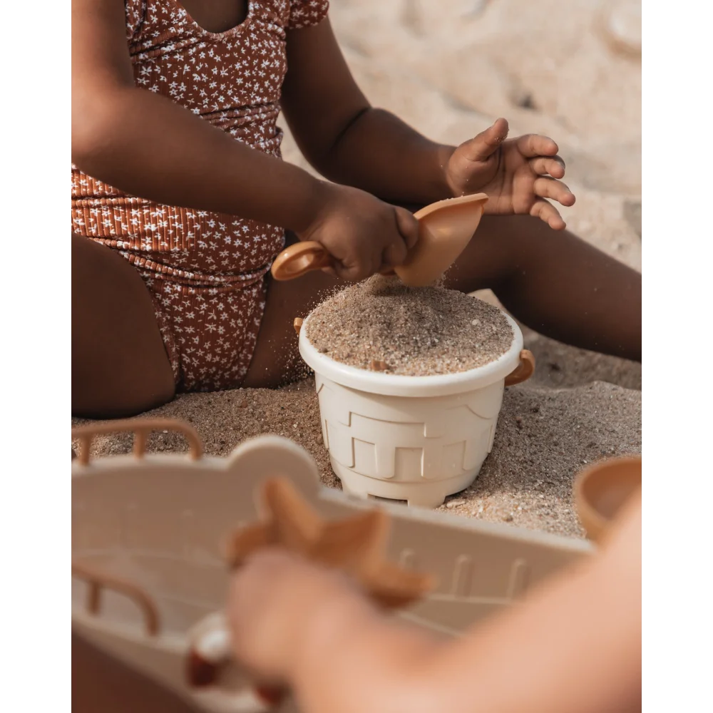 Weißer Kunststoffeimer gefüllt mit Sand oder Körnern für Sandspielzeug Schiff