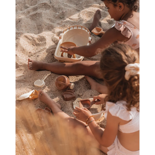 Kinder spielen mit Sand und Geschirrspielzeug am Strand mit Sandspielzeug Schiff