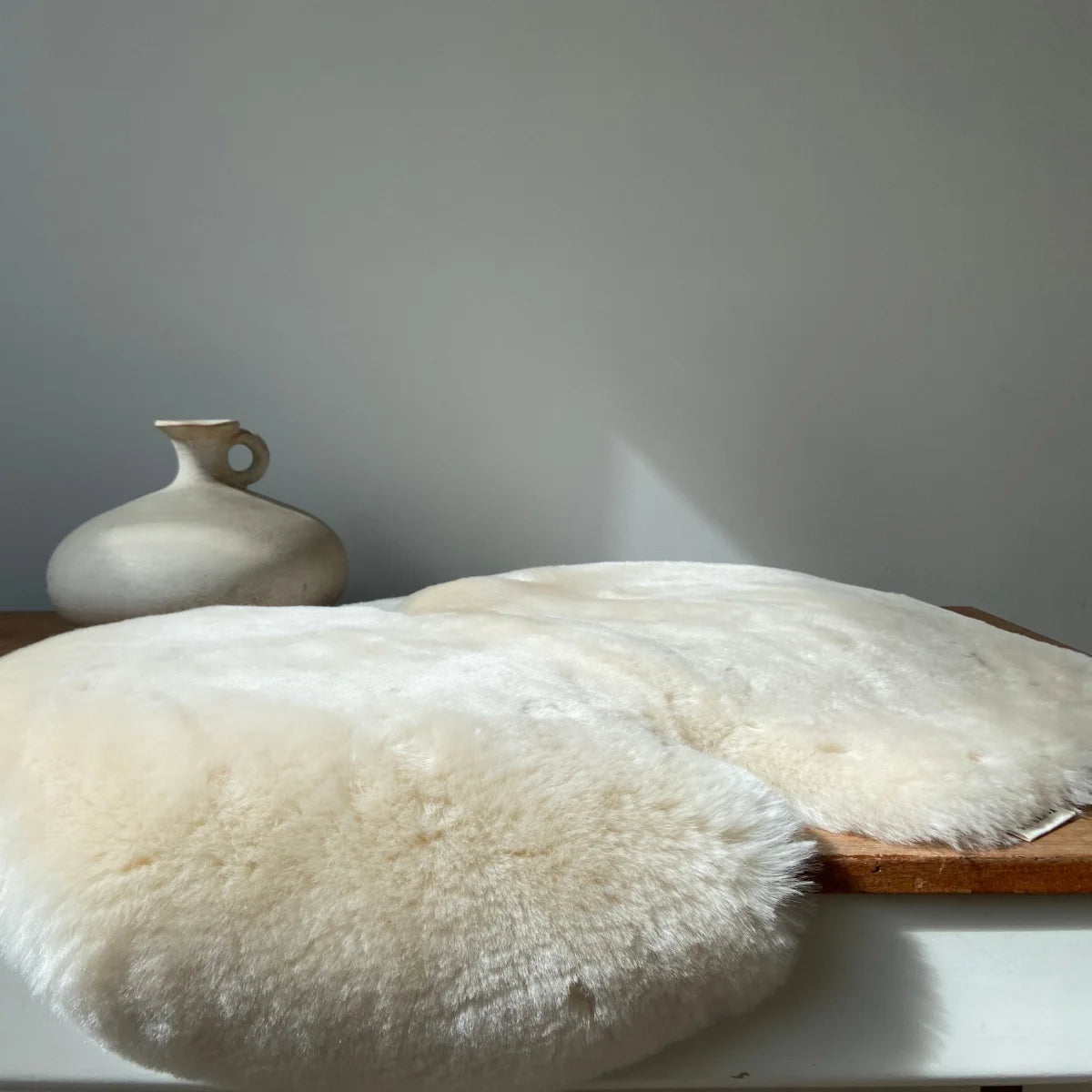 Weiches weißes Schaffell-Kissen mit flauschiger Textur und natürlichen Fellrändern, Schaffell Snuggler Fixed Harness Milk
