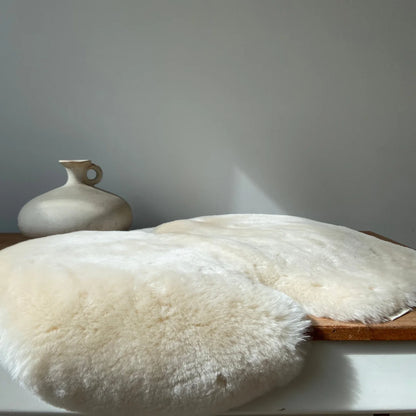 Weiches weißes Schaffell-Kissen mit flauschiger Textur und natürlichen Fellrändern, Schaffell Snuggler Fixed Harness Milk