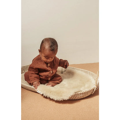 Baby in a woven basket with soft white lining, ideal for Schaffell Snuggler Peanut