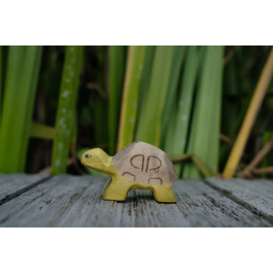 Kleine gelbe Holz-Schildkröte mit braunem Panzer und Schnitzmustern