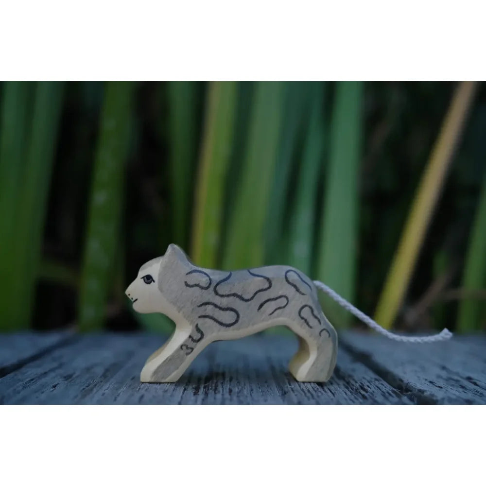 Leichter grauer Holzspielzeugkatze mit schwarzen Markierungen und weißem Schnurschwanz