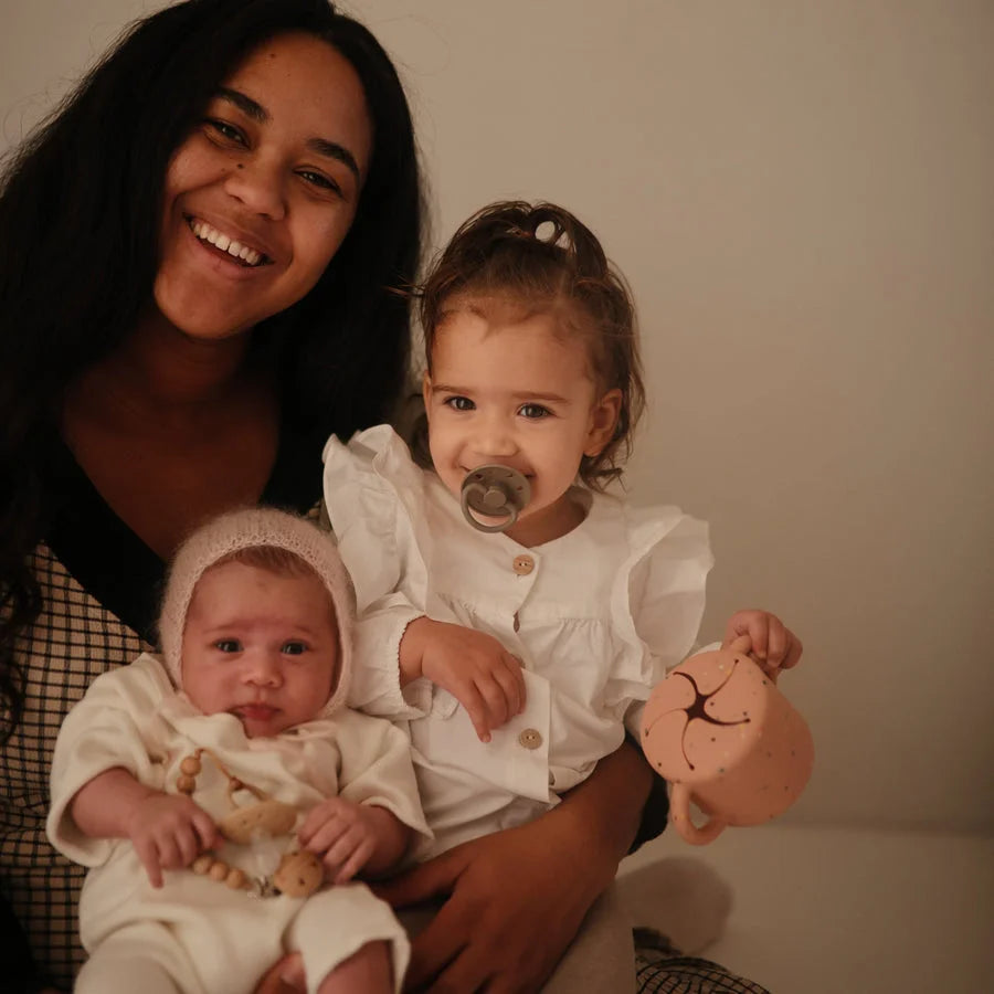 Lächelnde Frau mit zwei kleinen Kindern, einer mit Schnuller aus Silikon