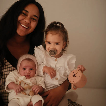 Lächelnde Frau mit zwei kleinen Kindern, einer mit Schnuller aus Silikon