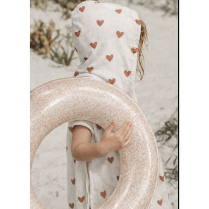 Ein durchscheinender, rosa schwimmring blushin coral mit sprenkeln, gehalten von einem kind, ideal für ökologische baby- & kinderprodukte