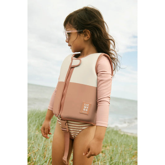 Kind schwimmt in rosé-cremefarbener Schwimmweste Dove Tuscany Rose mit Ärmeln