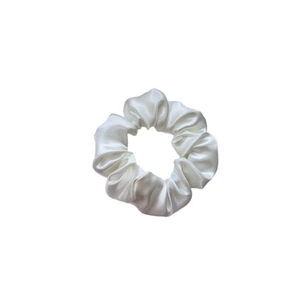 Ein eleganter offwhite satin scrunchie mit glänzendem finish und weicher geraffter textur von felice