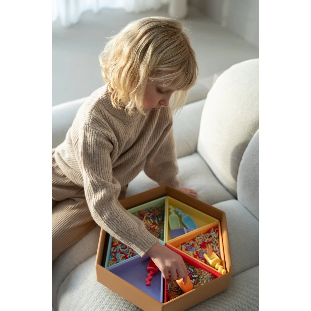 Sechseckige mandigo spielschale aus holz mit pastellfarbenen dreieck-einsätzen gefüllt mit konfetti und spielzeug