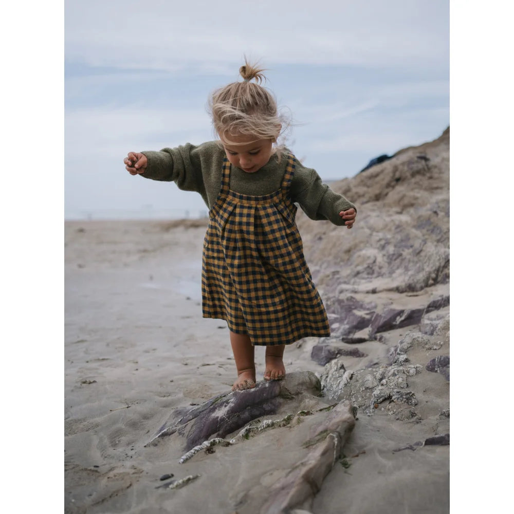 Junge im grünen Pullover und kariertem Pinafore für den Artichoke Wool Jumper