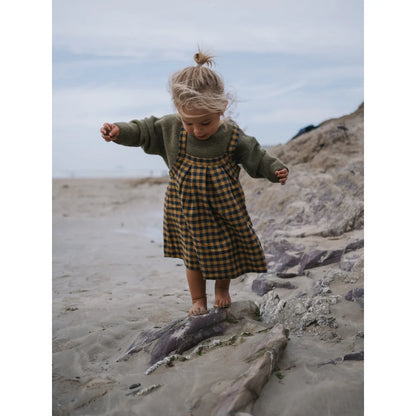 Junge im grünen Pullover und kariertem Pinafore für den Artichoke Wool Jumper