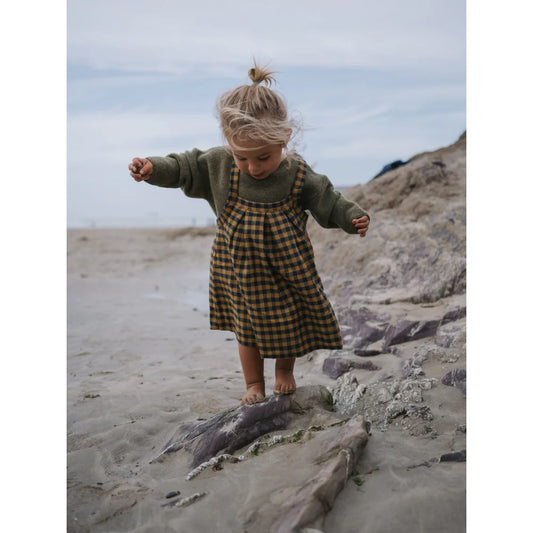 Junge im grünen Pullover und kariertem Pinafore für den Artichoke Wool Jumper