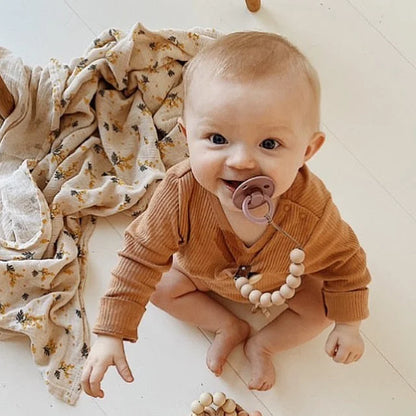 Lächelndes Baby mit Schnuller an Silikon Nuggikette aus Baumwolle
