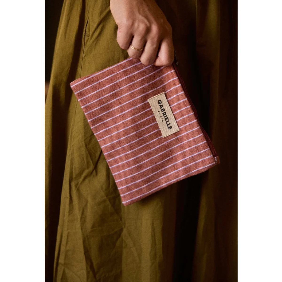 Kleine terrakotta-weiß gestreifte pouch aus gewebtem material mit beige etikett gabrielle paris für geschenke für neugeborene