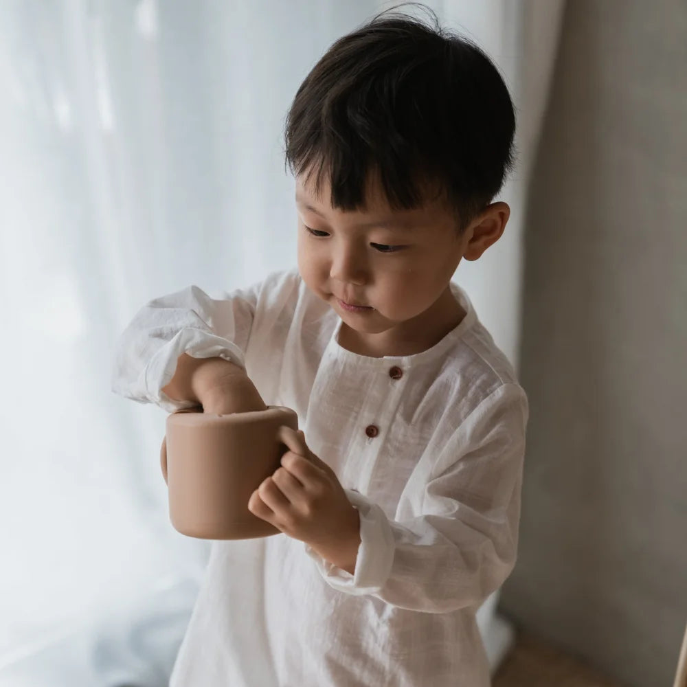 Junger Junge in weißem Shirt hält einen Becher von Snack Becher Natural