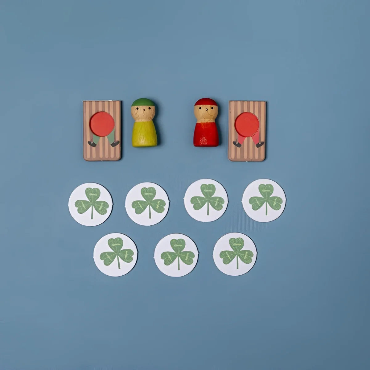 Holz-Peg-Puppen mit grünen und roten Hüten beim Snow Race Tiny Game zwischen gestreiften Toren