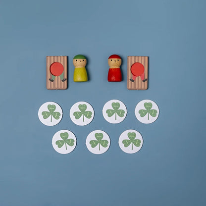 Holz-Peg-Puppen mit grünen und roten Hüten beim Snow Race Tiny Game zwischen gestreiften Toren