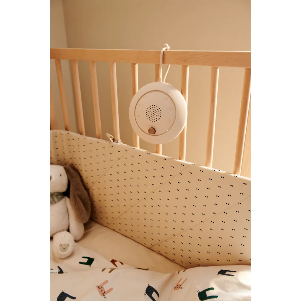 Weiße Baby-Soundmaschine Jordi | Sandy Oat an Gitterbett mit Lautsprechern und Knopf