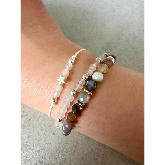 Ein weisses perlenarmband mit einem filigranen silbernen sternanhänger als nachhaltige geschenke für neugeborene