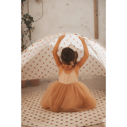 Mädchen im Tutu unter einem herzgemusterten Sonnenschutz von Lovely Roots