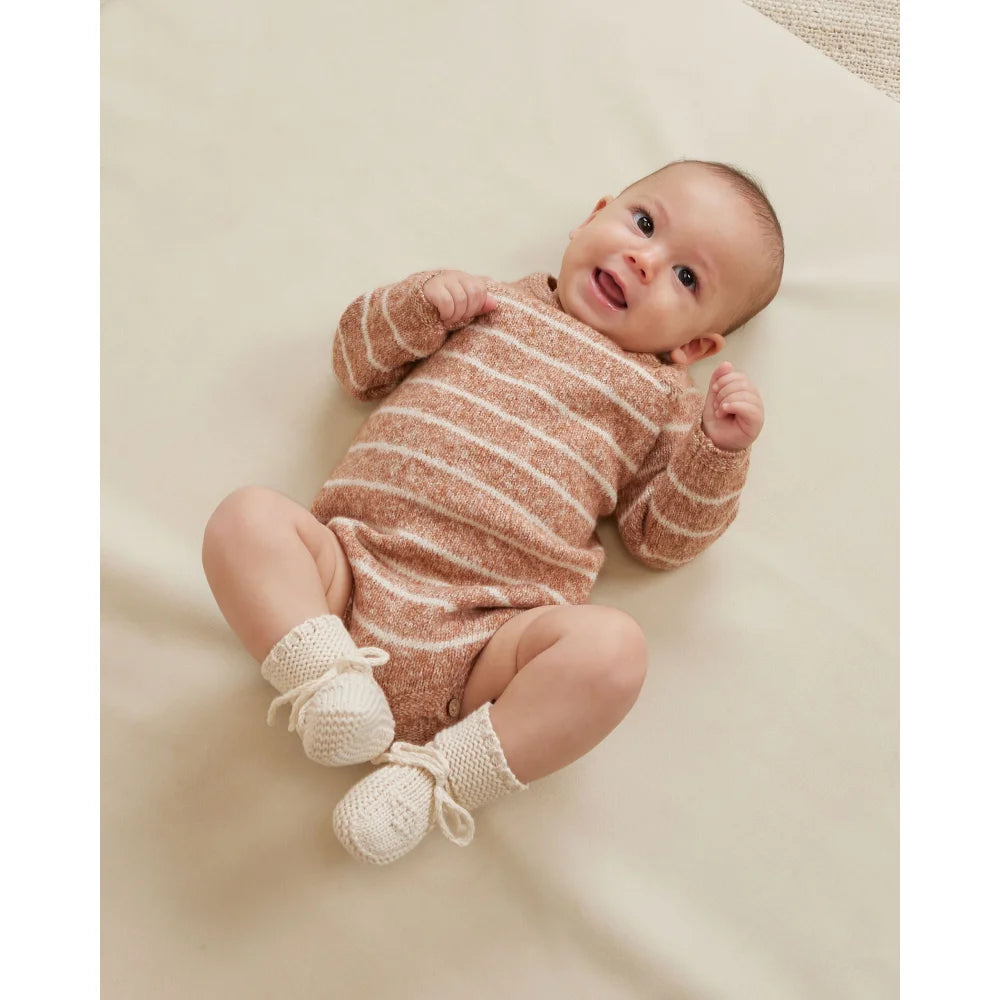 Baby in gestreiftem Overall und weißen Socken, Produkt Strick Schühchen Natural