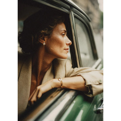 Frau mit braunen Locken aus grünem Oldtimer, trägt Mira Ohrringe aus 18k Gold Vermeil