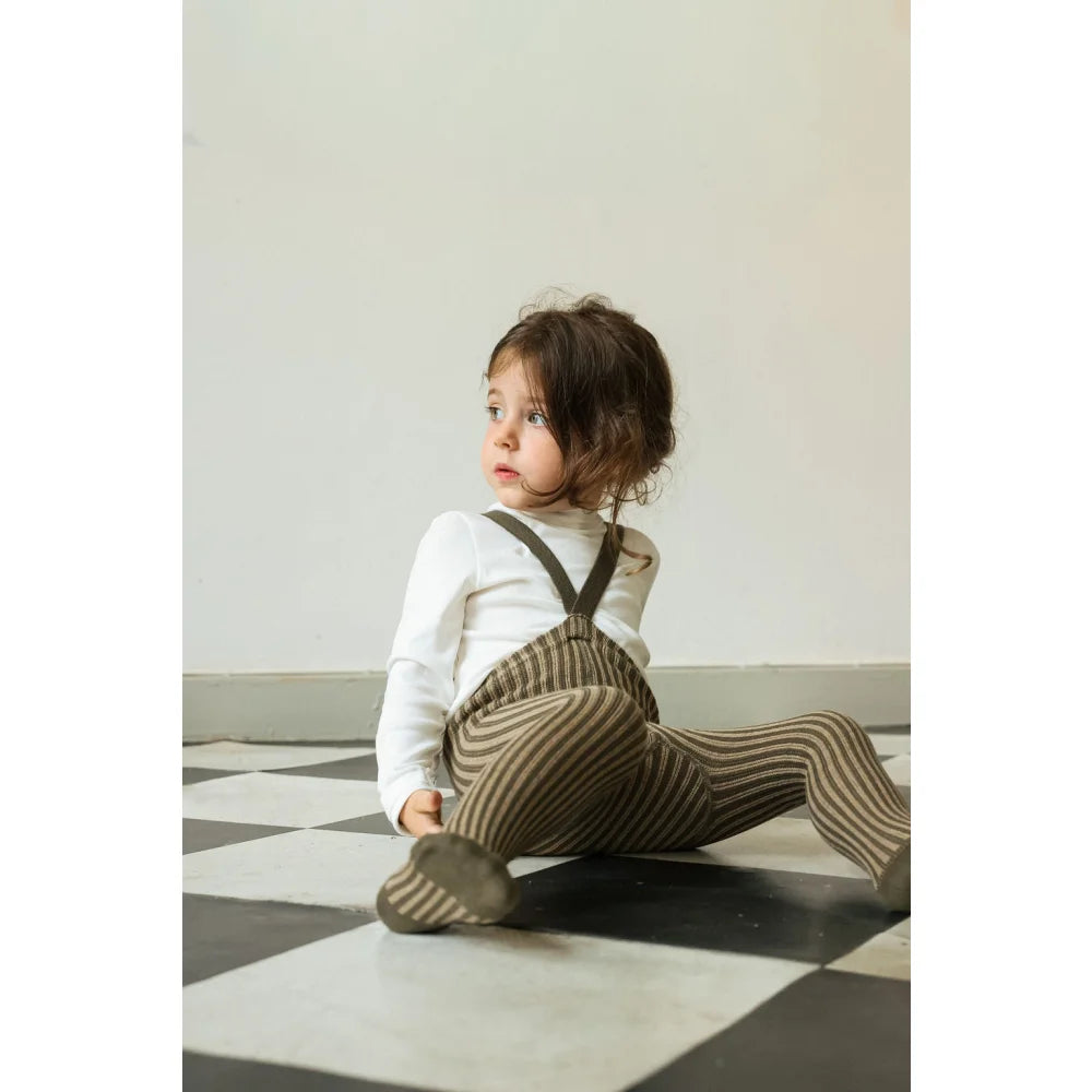 Kleiner Junge in gestreiften Trägerstrumpfhosen und weißem Langarmshirt