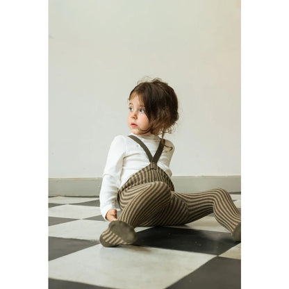 Kleiner Junge in gestreiften Trägerstrumpfhosen und weißem Langarmshirt