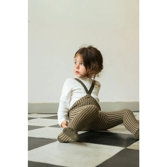 Kleiner Junge in gestreiften Trägerstrumpfhosen und weißem Langarmshirt