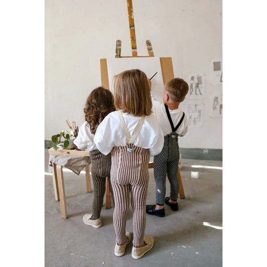Kinder in gestreiften Strumpfhosen mit Trägern Granola x Cream, weiße Hemden, Hosenträger, beige Schuhe