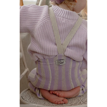 A child wearing a lavender and cream striped knit footless tights with matching suspenders viewed from the front