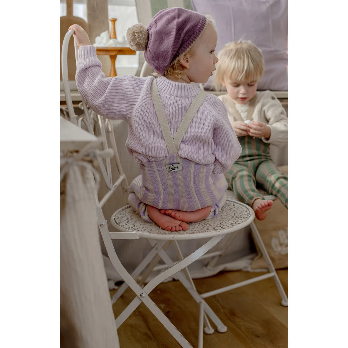 Ein kind trägt strumpfhose mit träger footless in lavendel und creme kombiniert mit weichem lavendelfarbendem strickpullover