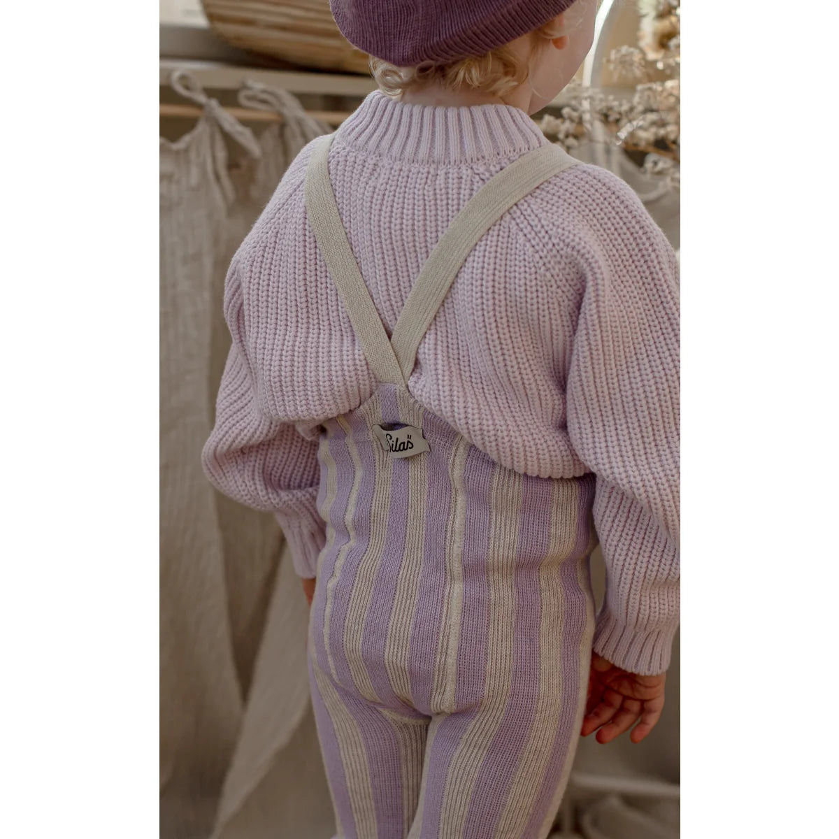 Ein kind trägt eine strumpfhose mit träger footless in lavendel und creme mit verstellbaren beigen trägern