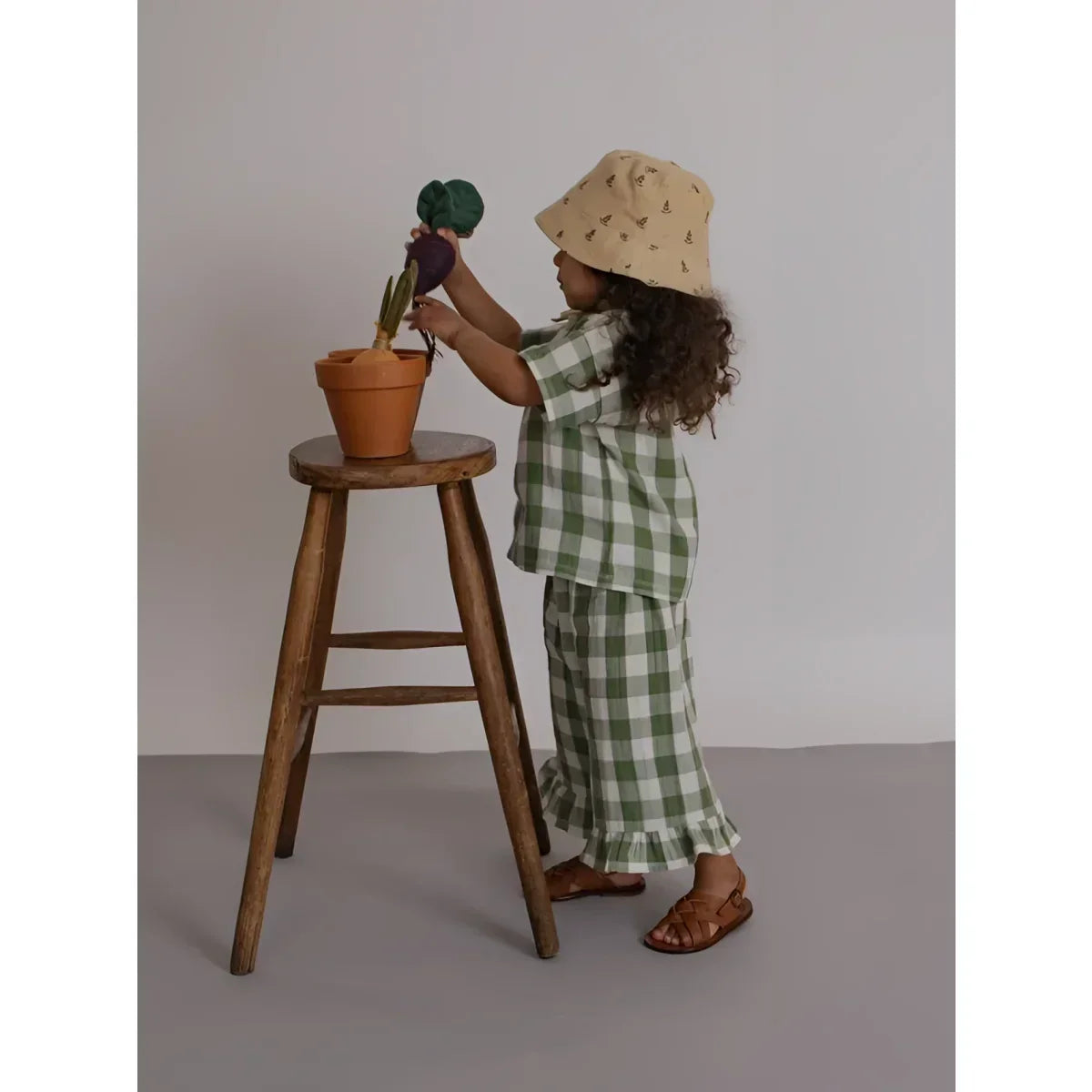 Kind im grün-weißen Karo-Zweiteiler mit Rüschensaum und Sun Hat Bucket Lavender Bloom