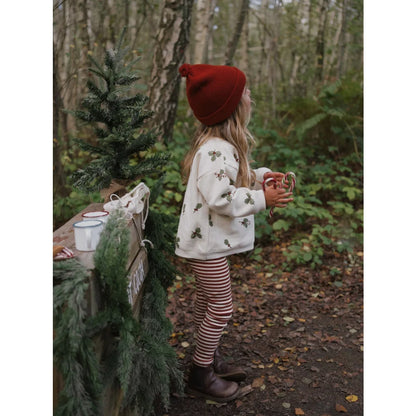 Kind mit rotem Hut und Weihnachts-Sweater in einem Wald