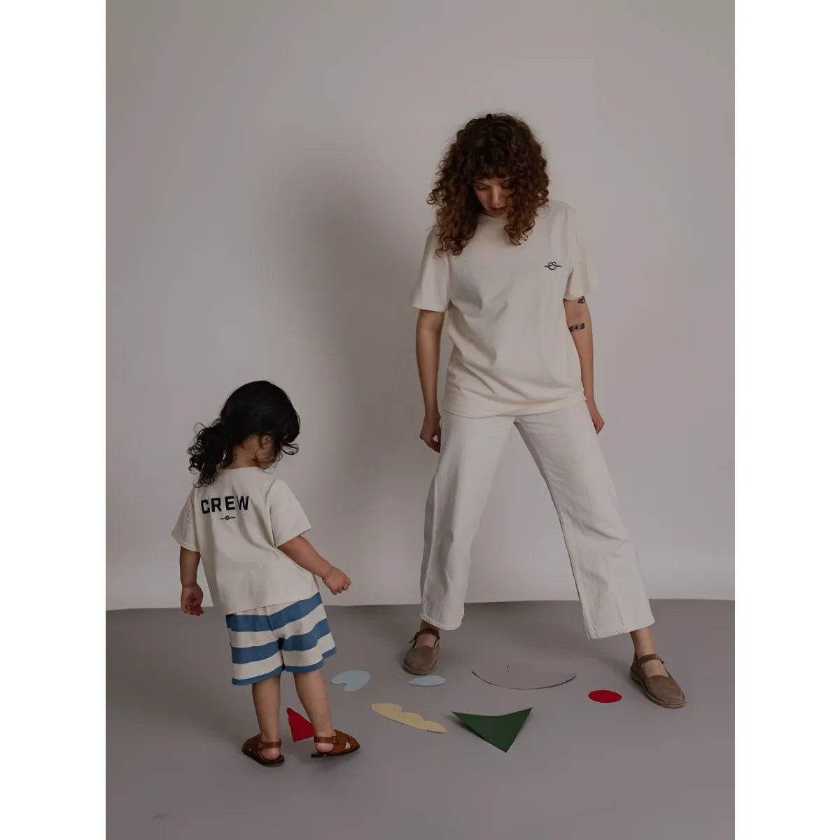 Eine frau trägt ein off-white t-shirt mit stickerei und weiße weite hose mit einem kind im minimalistischen outfit